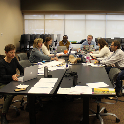 People working around two long office tables.