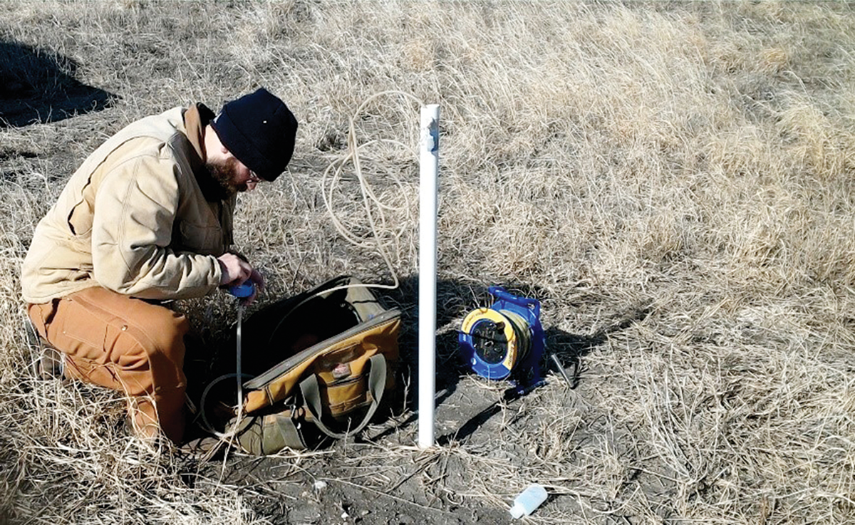 Soil scientist Matthew Streeter from the Iowa Geological Survey collects a groundwater sample from a shallow well installed at a reconstructed prairie in Iowa. Photo courtesy of the Iowa Geological Survey.