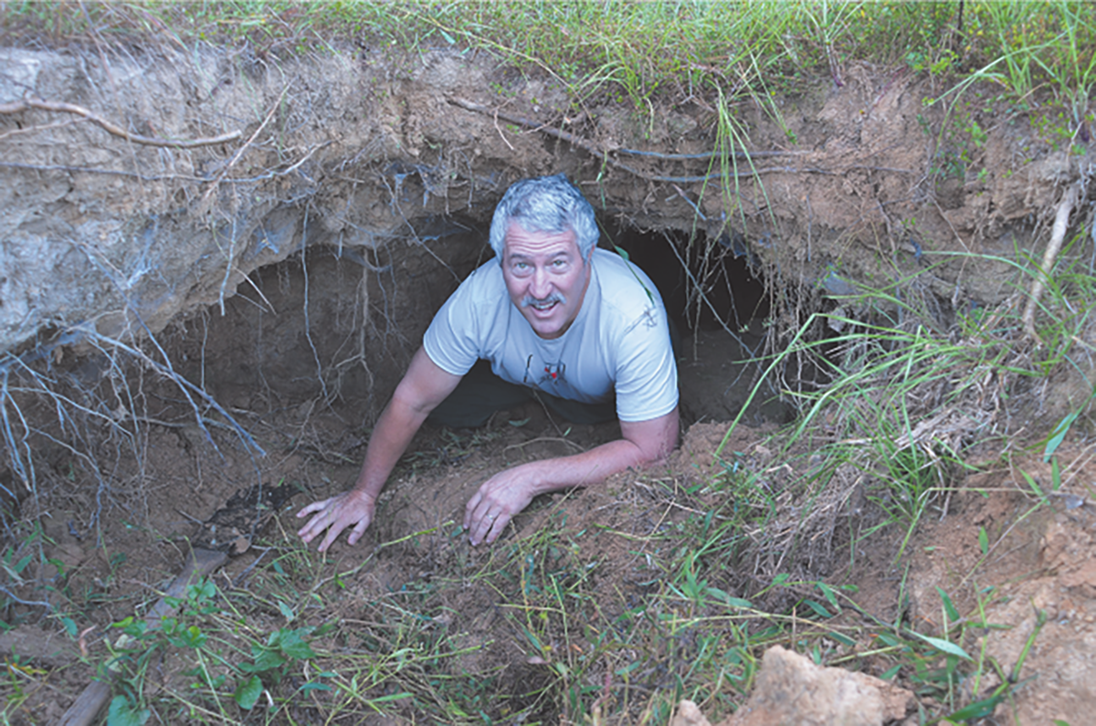 Dr. Glenn Wilson crawls out of a soil pipe into a gully, demonstrating the large size soil pipes can reach by internal erosion before they collapse.