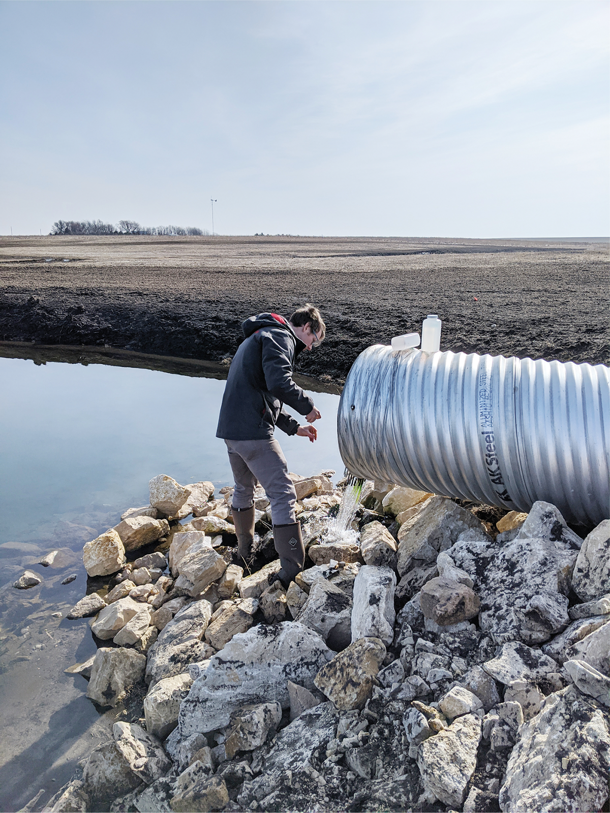 Timothy Neher collects a water quality sample from a wetland located in the Black Hawk Lake watershed. Photo by Ji Yeow Law.