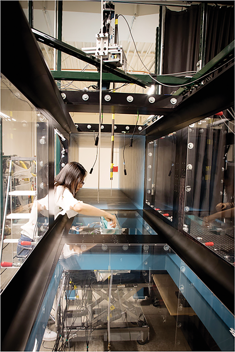 Graduate student and primary author Bo Gao installs sensors within the soil tank and wind tunnel experimental apparatus. Photo by Kathleen Smits.