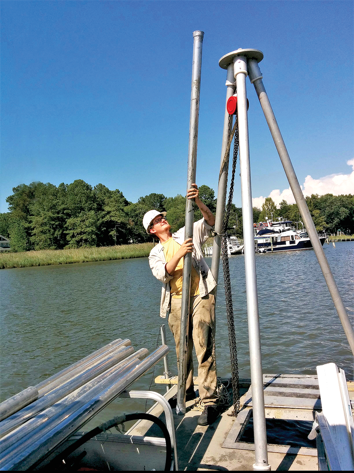 Barret Wessel looks up at a successful soil core sample from his graduate work on Chesapeake Bay. This one contained about three meters of soil, pulled up through the deck hatch open near Wessel’s feet. Photo courtesy of Barret Wessel.