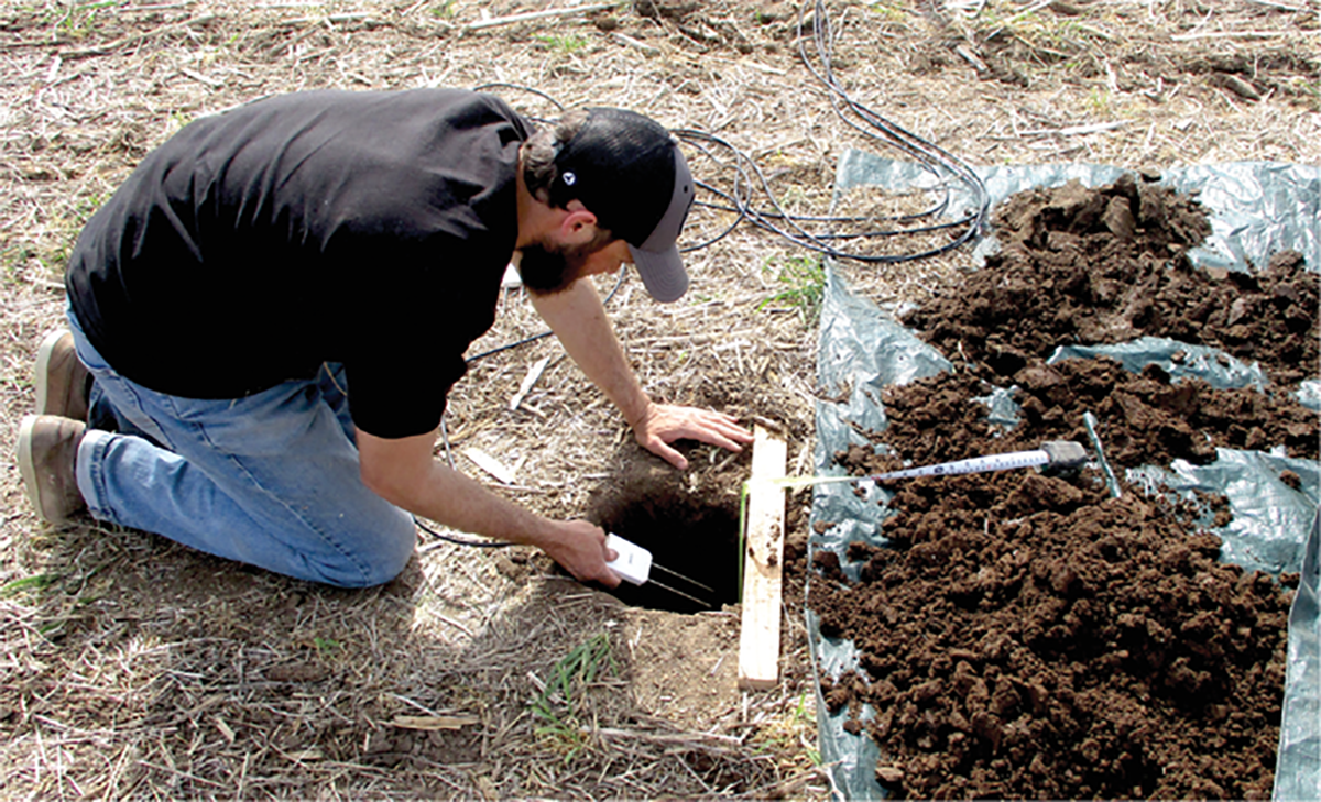 Lead author Pedro Rossini installs soil water reflectometers in a commercial field at the Flickner Innovation Farm. Photo courtesy Andres Patrignani.