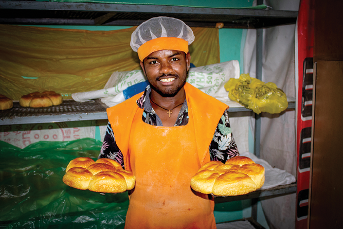 A baker at Duwame Bakery shows off the golden brown orange- fleshed sweet potato (OFSP) bread. Photo by Frezer Asfaw.