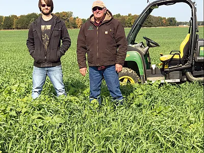 A Michigan grower and his grandson standing in a field of mixed cover crop species, which provide numerous benefits, including the ability to have an advantage when bidding for rented land.