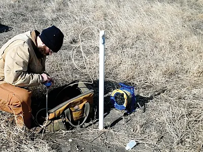 Soil scientist Matthew Streeter from the Iowa Geological Survey collects a groundwater sample from a shallow well installed at a reconstructed prairie in Iowa. Photo courtesy of the Iowa Geological Survey.