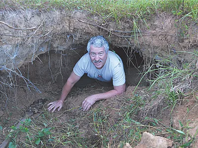 Dr. Glenn Wilson crawls out of a soil pipe into a gully, demonstrating the large size soil pipes can reach by internal erosion before they collapse.