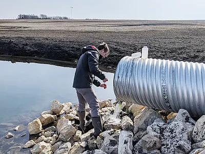 Timothy Neher collects a water quality sample from a wetland located in the Black Hawk Lake watershed. Photo by Ji Yeow Law.