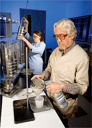 Researchers prepare to separate soil aggregates and wash a sep- arated aggregate sample off of a soil sieve into a container to determine the amount and origin of the carbon sequestered in the sample. Photo by Stephen Ausmus, USDA-ARS.